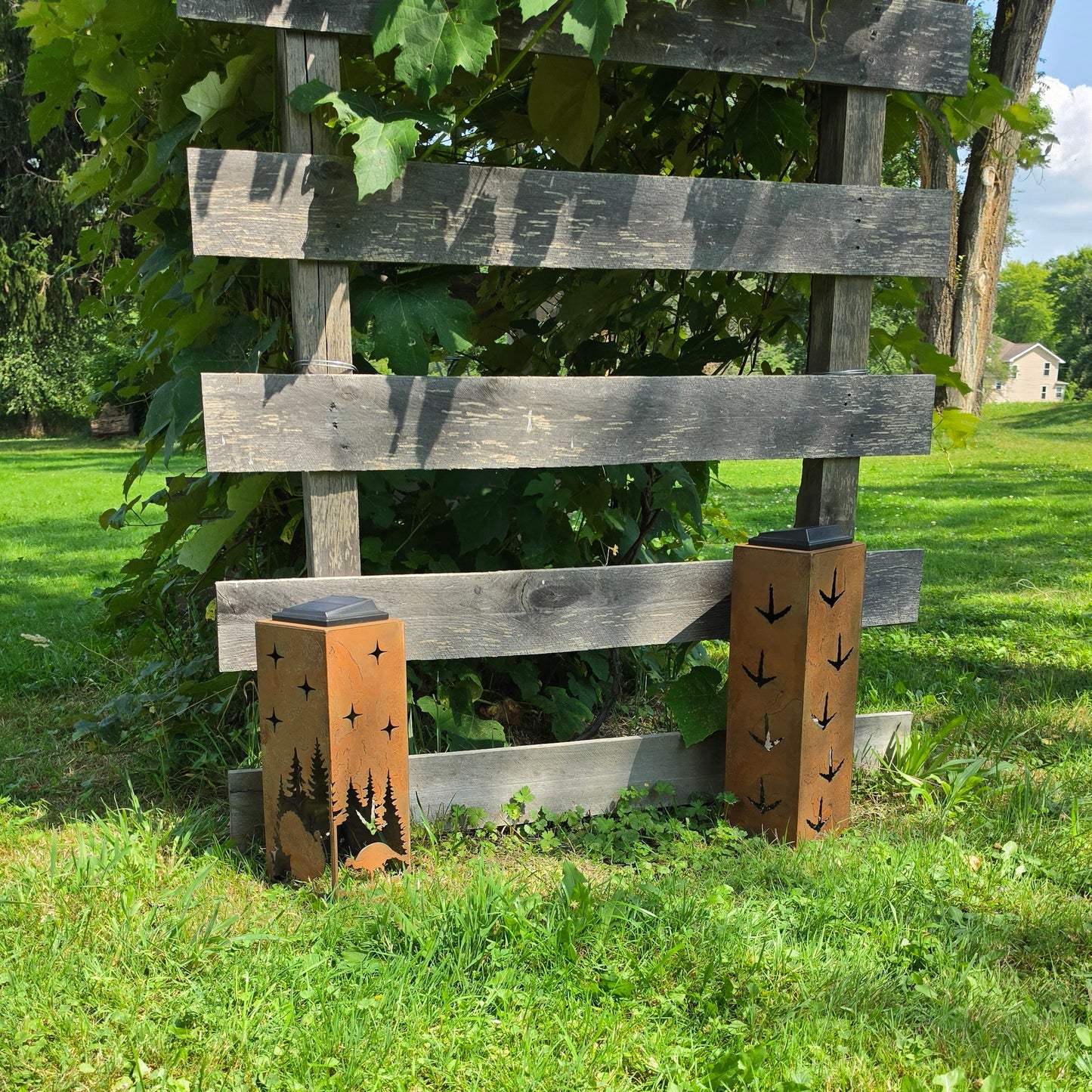 Rustic metal turkey themed solar pillars outdoors showing alternate sides in front of grape vines