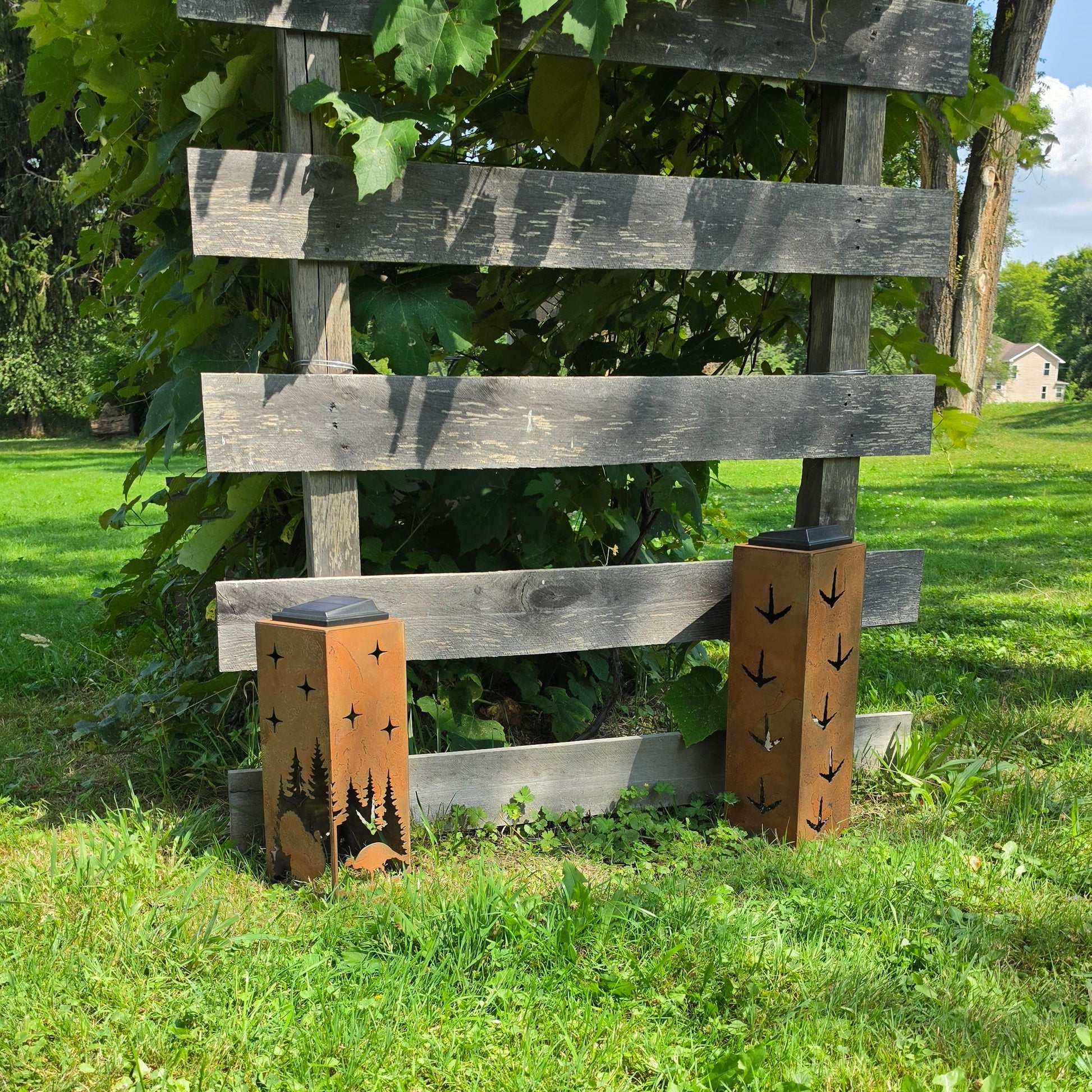 Rustic metal turkey themed solar pillars outdoors showing alternate sides in front of grape vines
