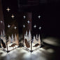 Two tall rectangular metal lanterns with laser-cut silhouettes of trees, turkeys, and stars, glowing with warm light in a dark room.