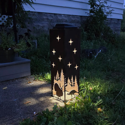 Metal solar lantern with turkey design glowing at dusk on a patio