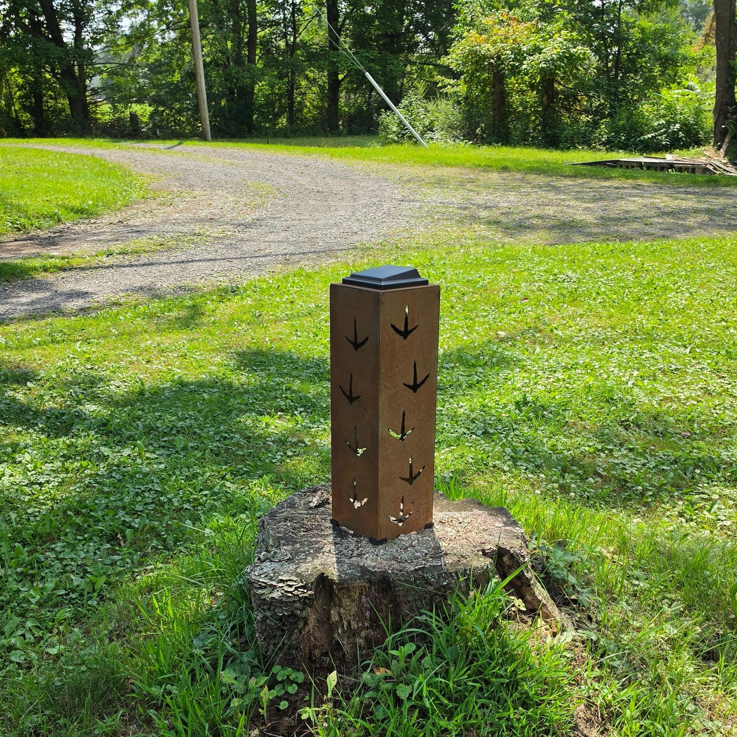 Tall rustic solar pillar with turkey prints outdoors on a stump