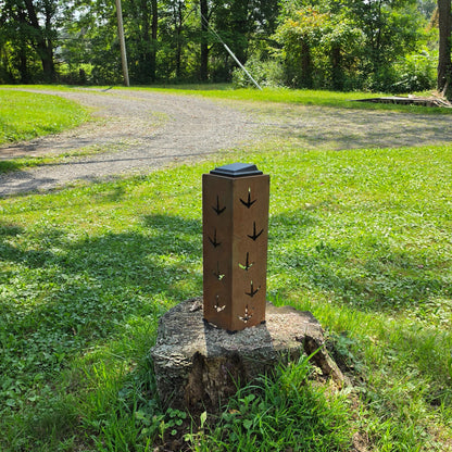 Tall rustic solar pillar with turkey prints outdoors on a stump