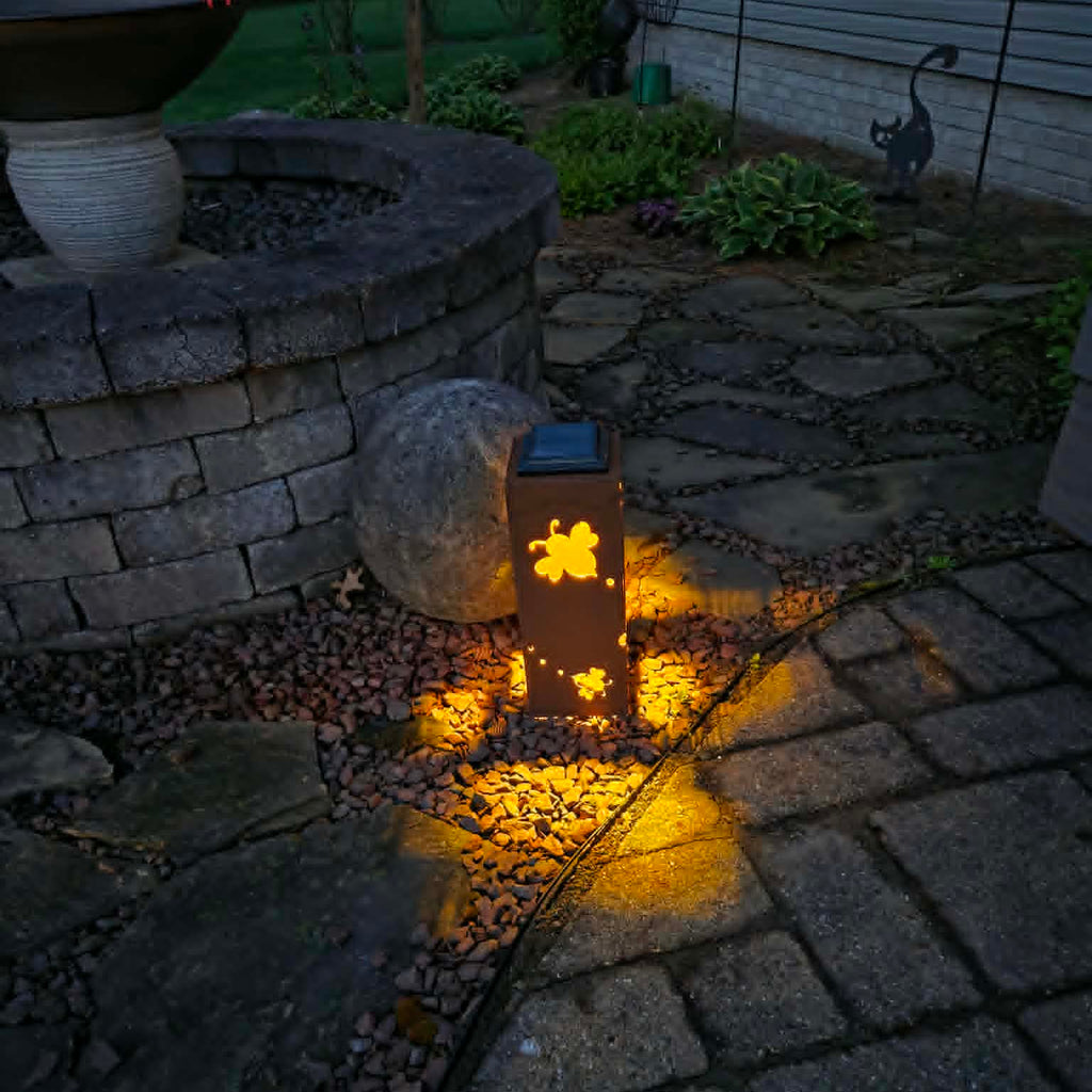Solar light embedded in a garden pathway with a stone wall and plants in the background.