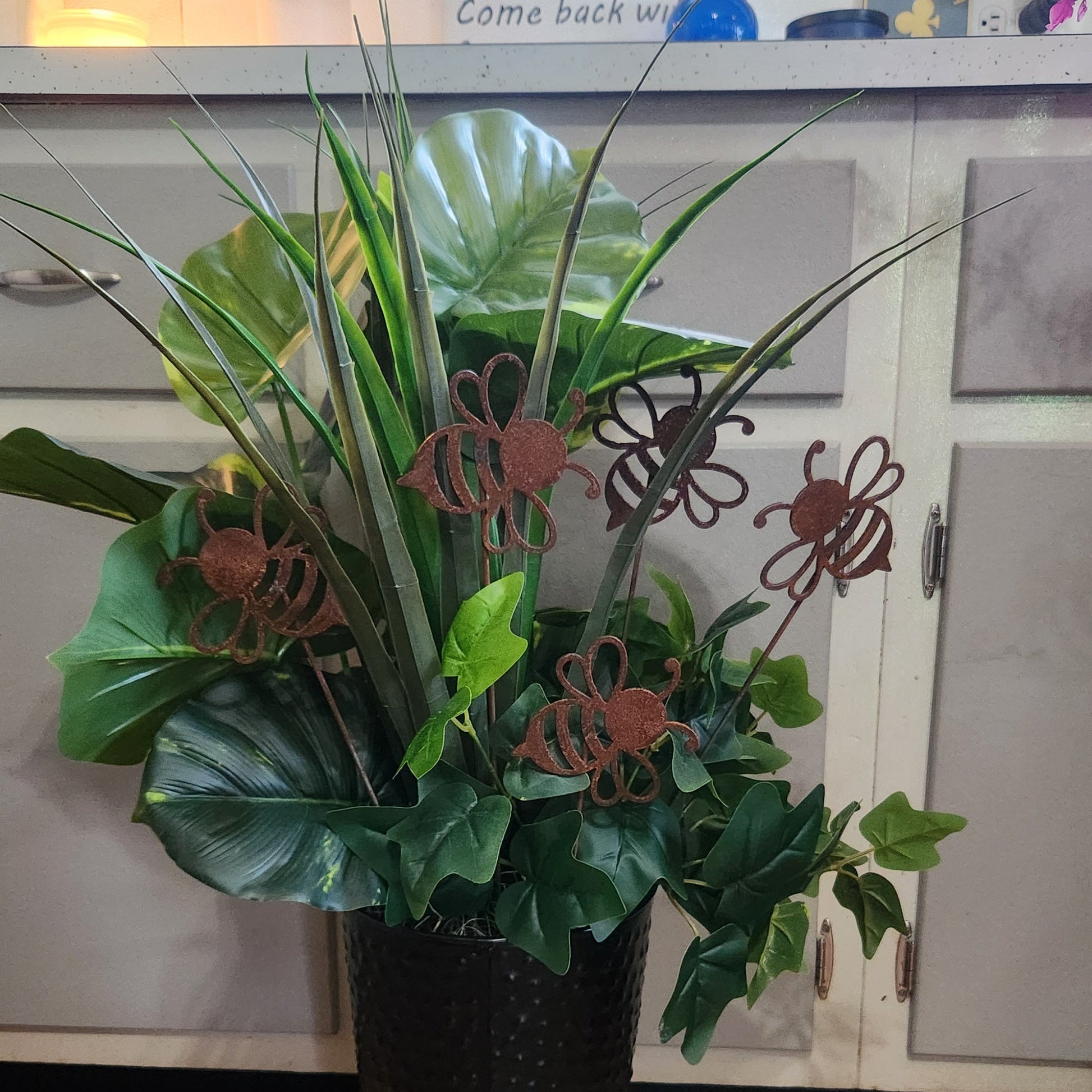 Potted plant with decorative metal bee sculptures in a kitchen setting