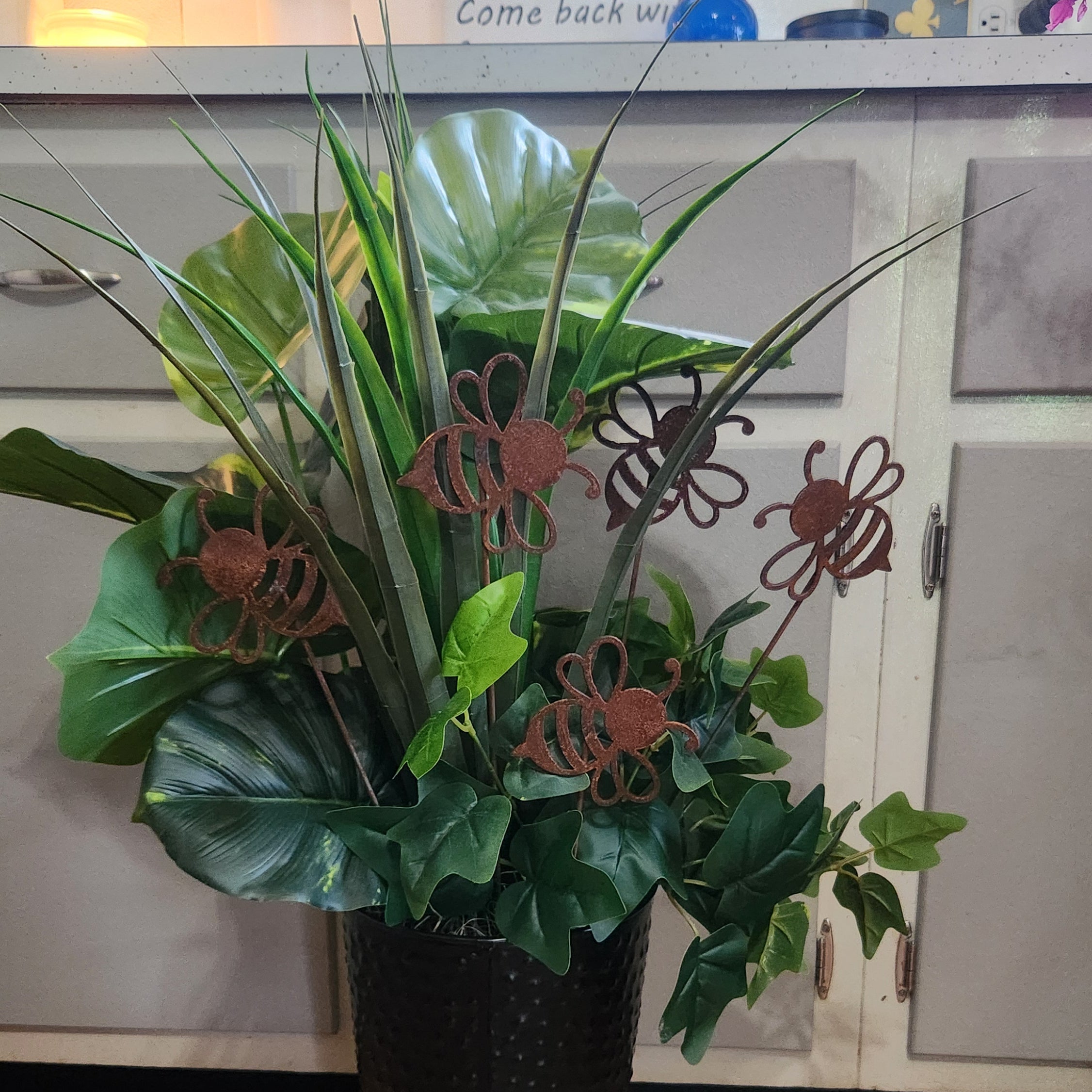 Potted plant with decorative metal bee sculptures in a kitchen setting