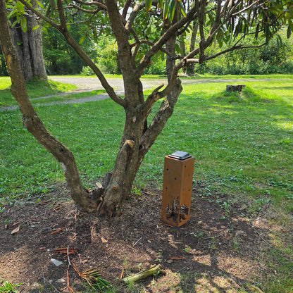 Rustic bear solar pillar outdoors next to a bush
