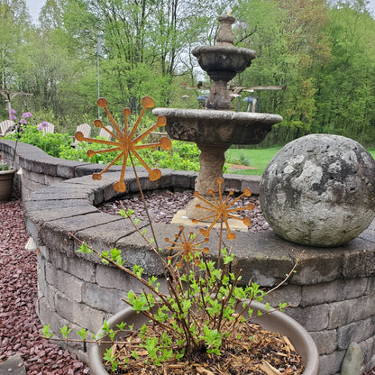 Rustic metal plant stakes in front of a fountain