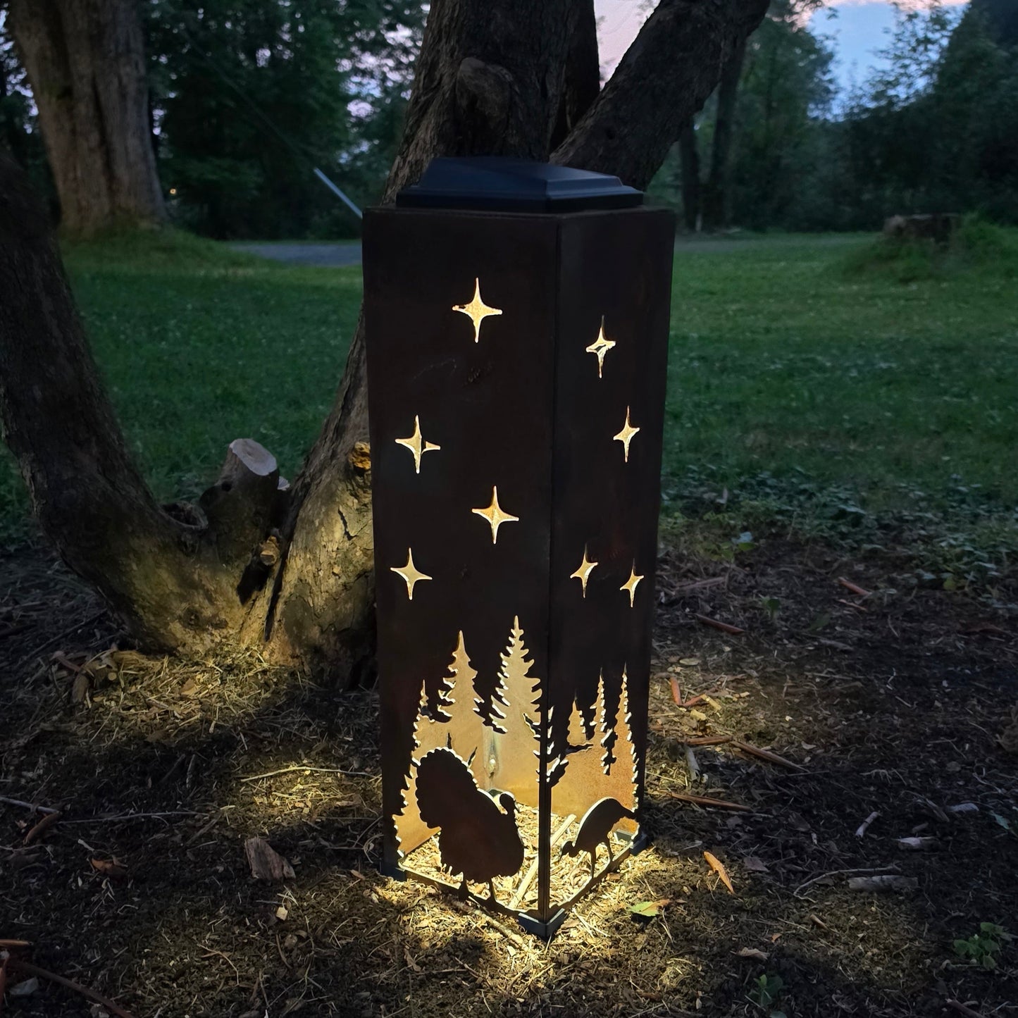Rustic turkey solar pillar glowing at night by a bush