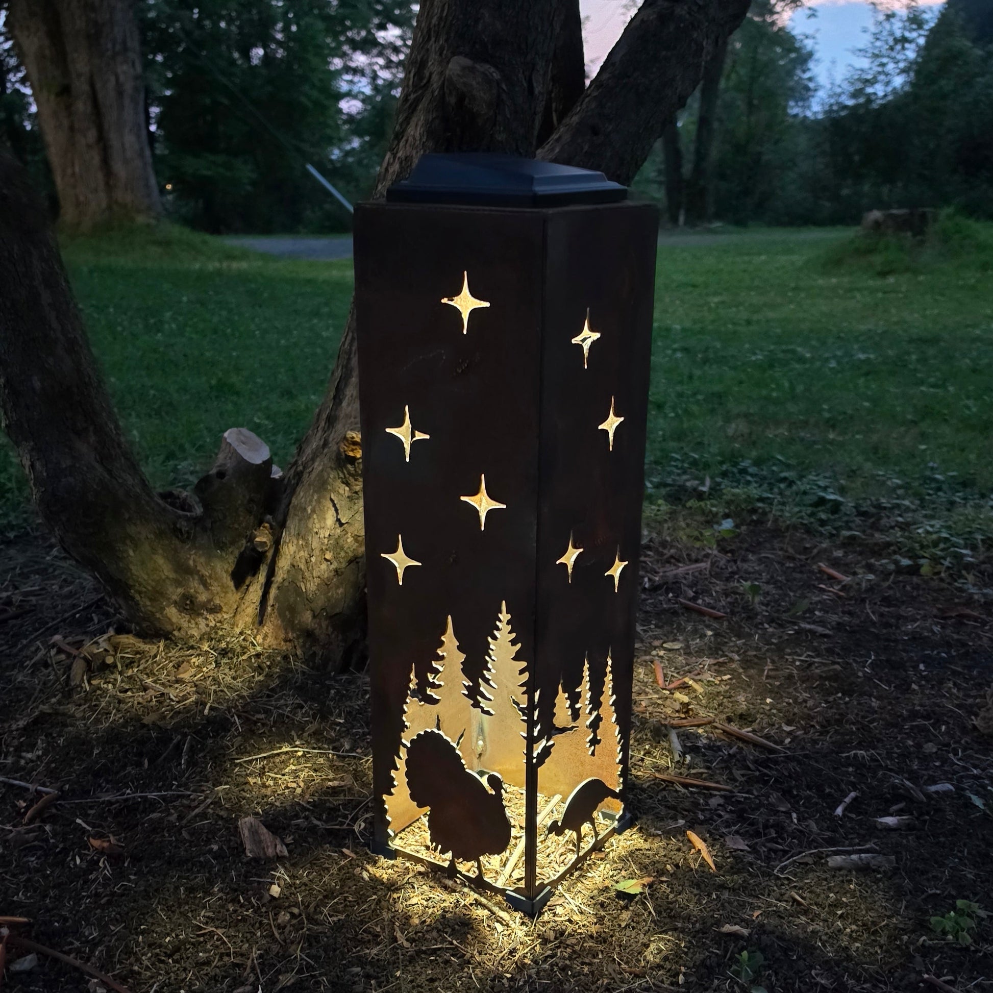 Rustic turkey solar pillar glowing at night by a bush