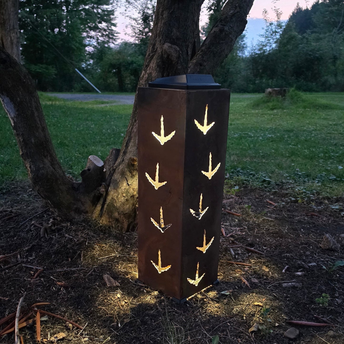 Rustic metal solar pillar glowing at dusk with turkey prints