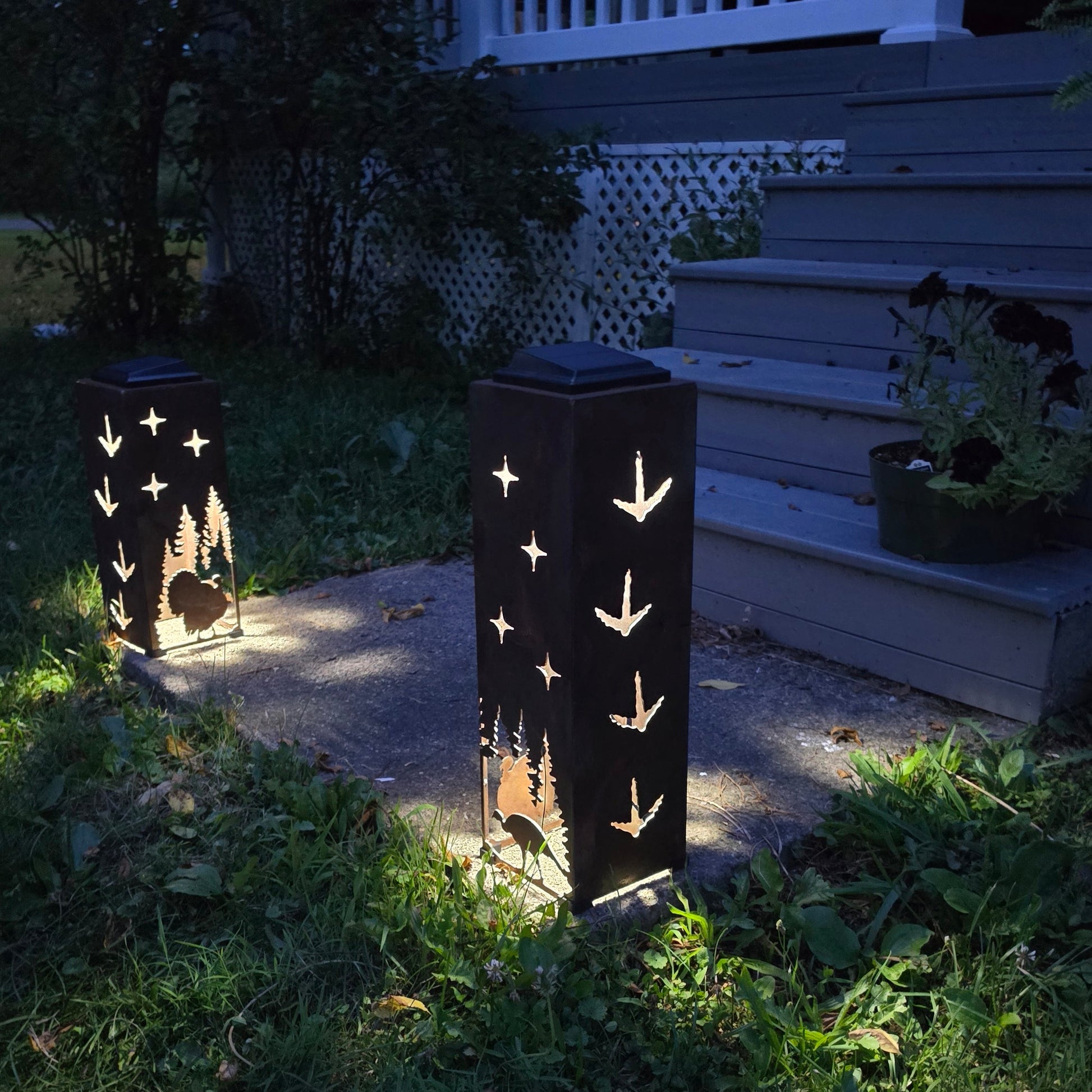 Rustic Solar pillars glowing at dusk showing both sides on front patio