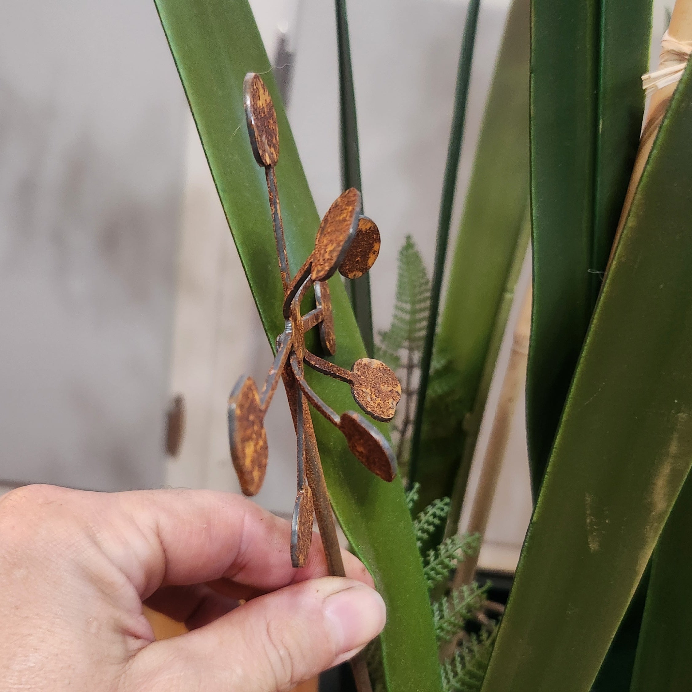 Rustic metal bendable dandelion plant stake up close to show detail.