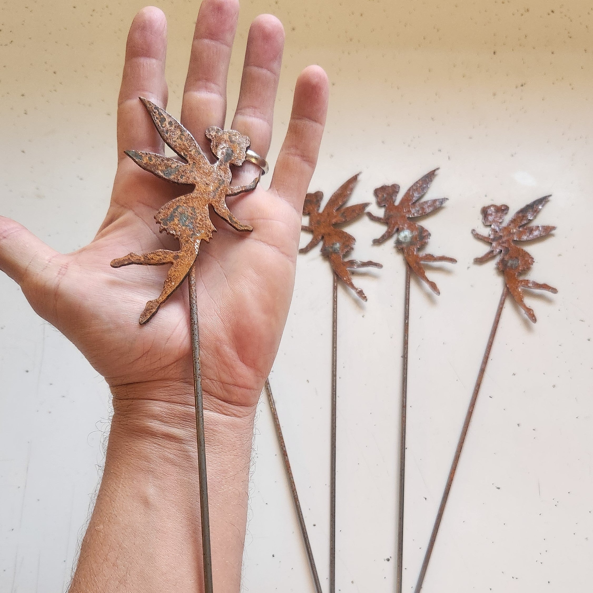 Rustic metal fairy plant stake in hand for size comparison.