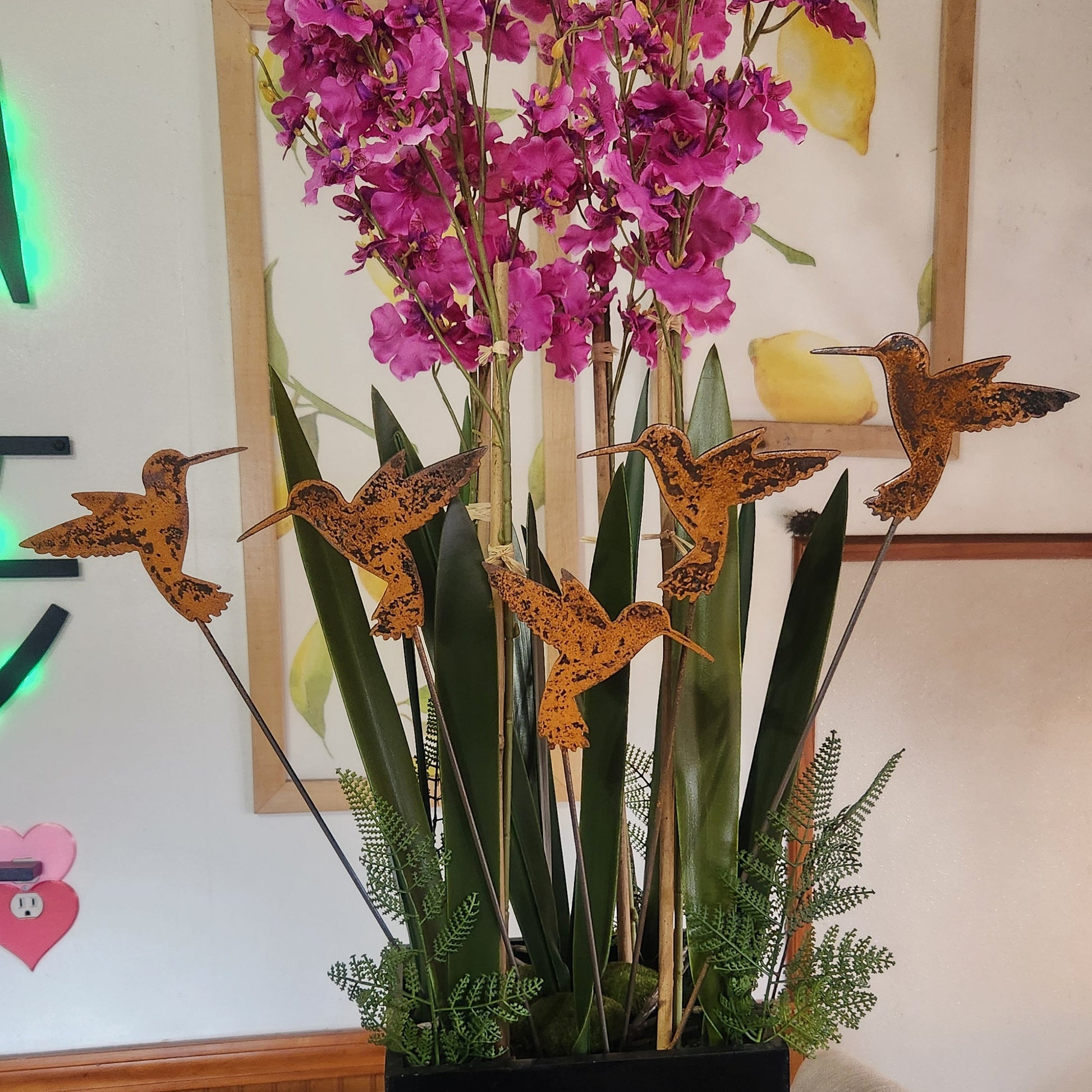 Rustic metal hummingbird plant stakes in fake plant.
