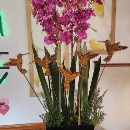 Rustic metal hummingbird plant stakes in fake plant.