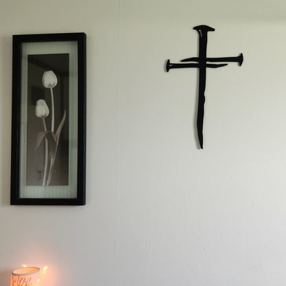 thick black metal nail cross on white wall